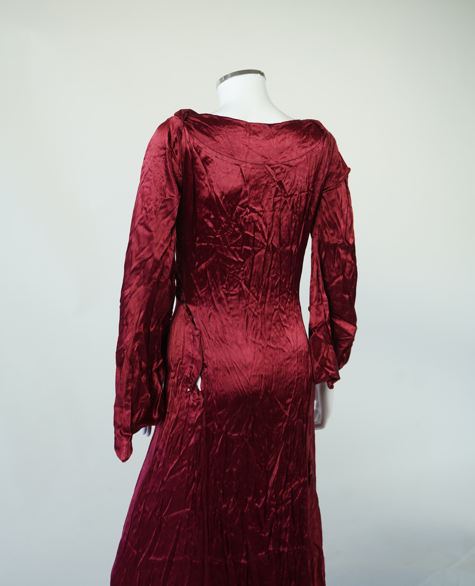 A 1920’s light green silk evening cape with hand batik borders and label: Tito de Canival Mode, together with a navy ladies two piece suit and a maroon satin evening dress. Cape 100cm long. Condition - cape good, navy tw